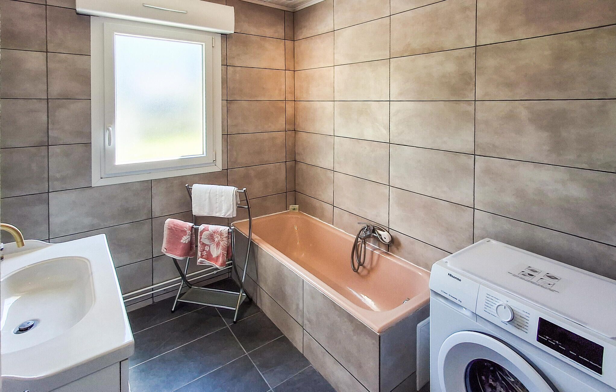 A modern bathroom with a bathtub, a sink, and a washing machine.