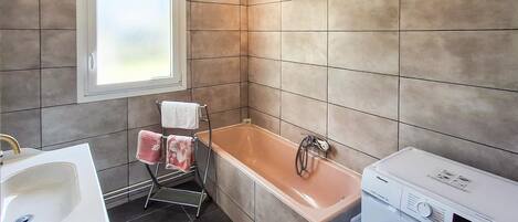 A modern bathroom with a bathtub, a sink, and a washing machine.