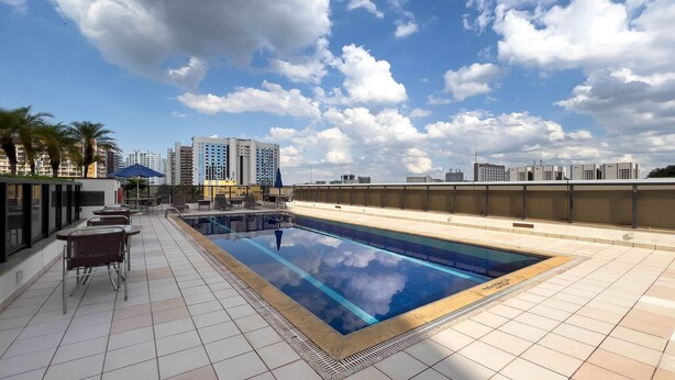 A rooftop pool with clear blue water, surrounded by tiled flooring and lounge chairs. - Flat at Comfort Suites Brasilia Coa0314 (Brasília)