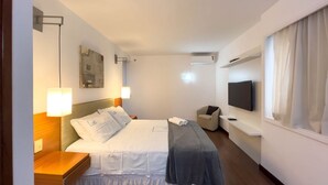 A hotel room with a bed, bedside lamps, a TV, a chair, and a window with curtains. - Flat at Comfort Suites Brasilia Coa0314 (Brasília)