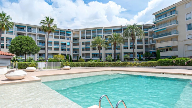 Un hotel con piscina, varios balcones y palmeras.
