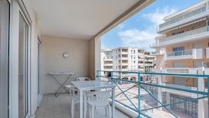 Un balcón con mesa y sillas, un tendedero y vistas a edificios de varios pisos.