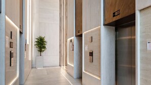 A modern hallway with elevators, a plant, and illuminated wall panels. - Modern Studio at Paragon (Dubai)