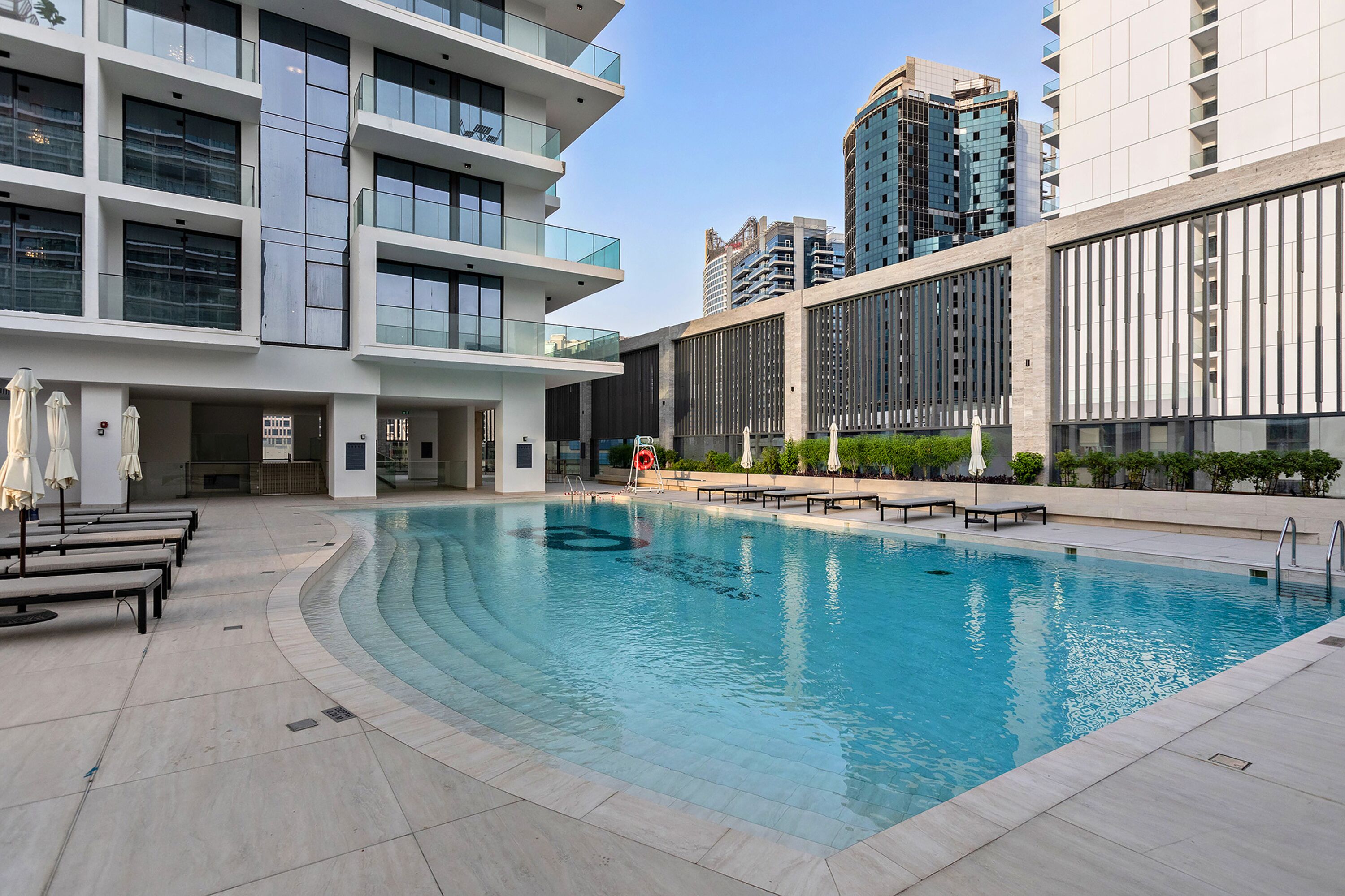 Un bâtiment moderne doté d’une piscine, d’un espace extérieur aménagé et offrant une vue sur un ciel dégagé.