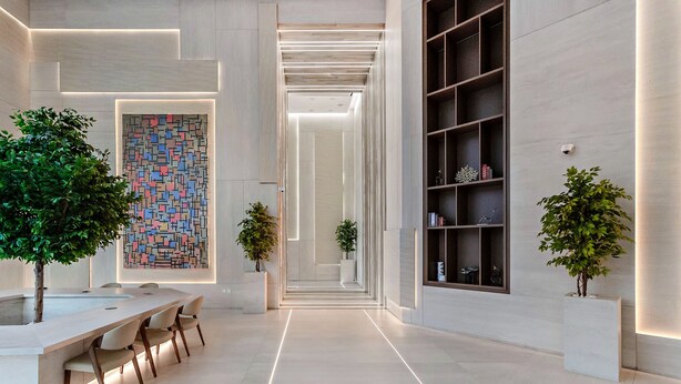 A modern interior with a long hallway, a dining area with a table and chairs, and a large bookshelf. - Modern Studio at Paragon (Dubai)