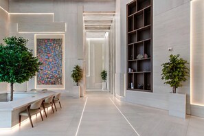 A modern interior with a long hallway, a dining area with a table and chairs, and a large bookshelf. - Modern Studio at Paragon (Dubai)
