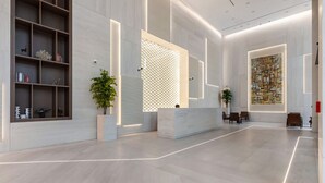 A modern lobby with a reception desk, seating area, and decorative shelves. - Modern Studio at Paragon (Dubai)