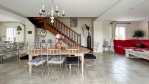 A spacious living area with a dining table, chairs, a red sofa, and a staircase. - Gite avec piscine et jacuzzi (Seigy)