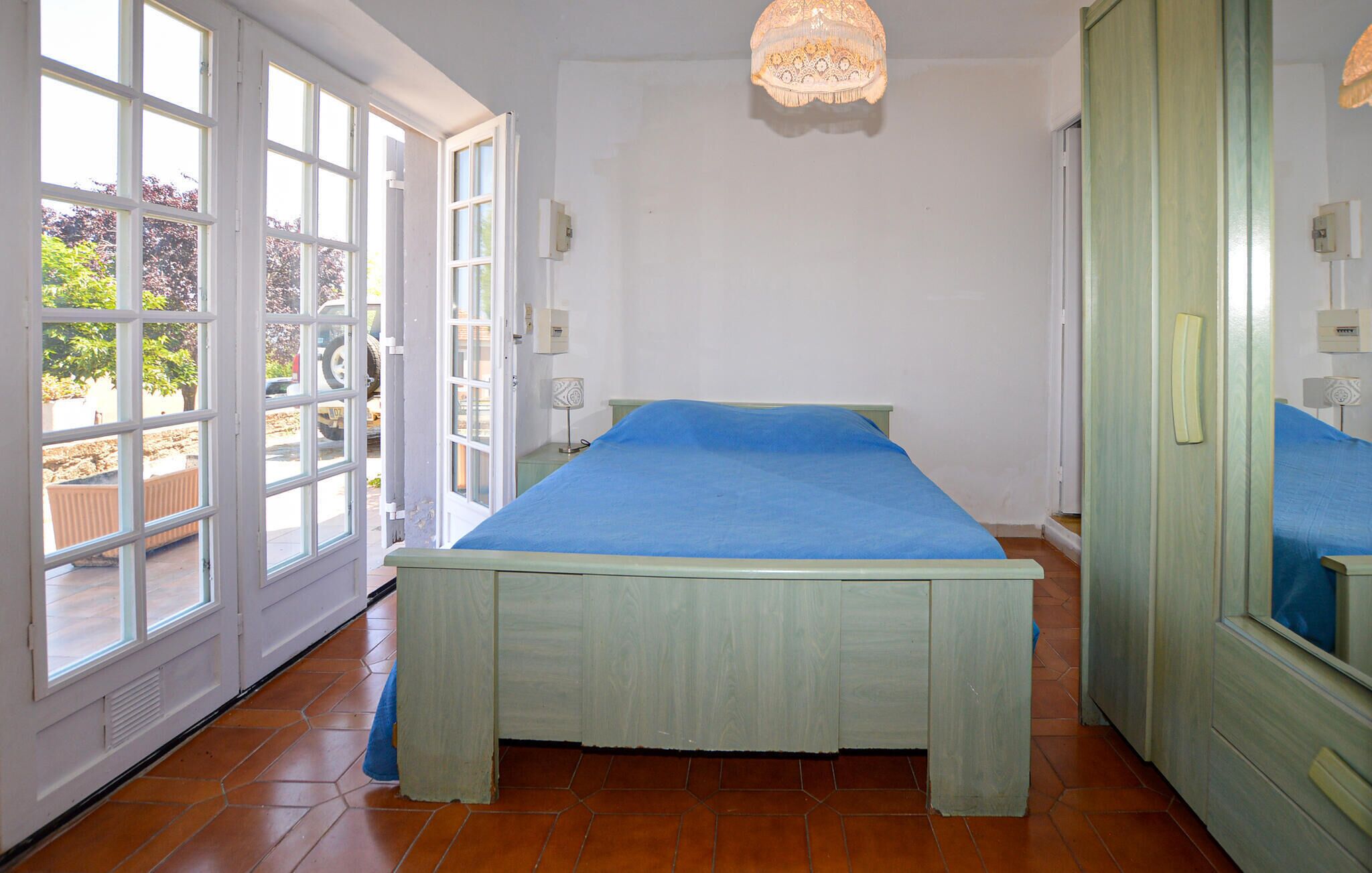 Une chambre à coucher avec un lit, une grande fenêtre et une porte donnant sur l’extérieur.