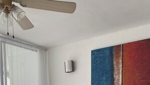 Ein modernes Wohnzimmer mit einem braunen Ecksofa, einem Glastisch und einem Deckenventilator.