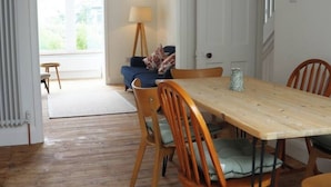 A dining area with a wooden table and chairs, a lamp, and a view of the outdoors through a window.