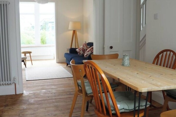 A dining area with a wooden table and chairs, a lamp, and a view of the outdoors through a window.