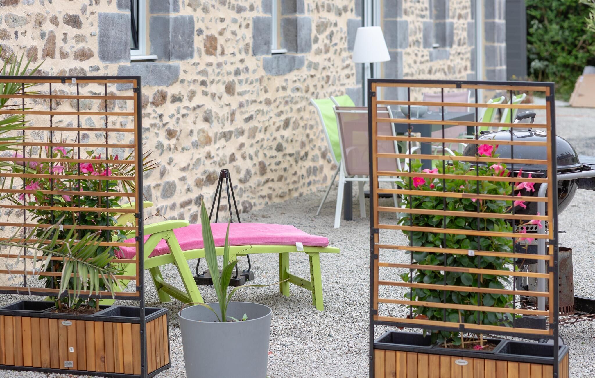 Outdoor seating with a stone wall backdrop, a grill, and potted plants.