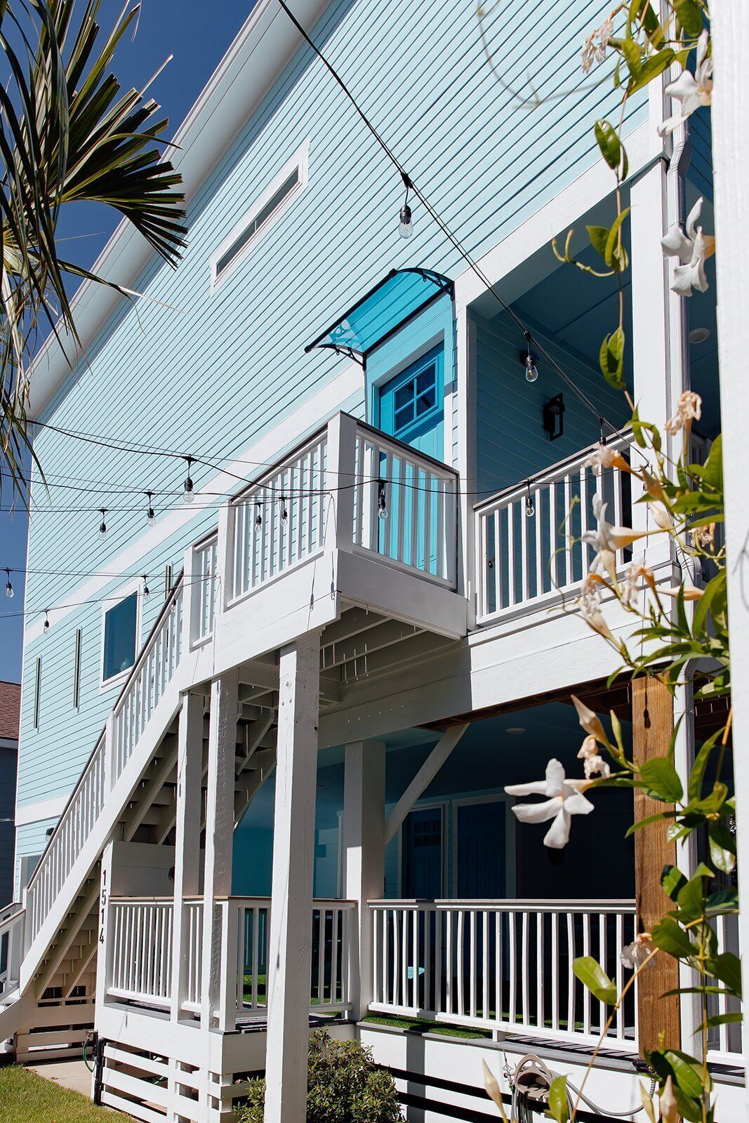 A two-story building with a blue exterior, white railings, and a covered porch area.