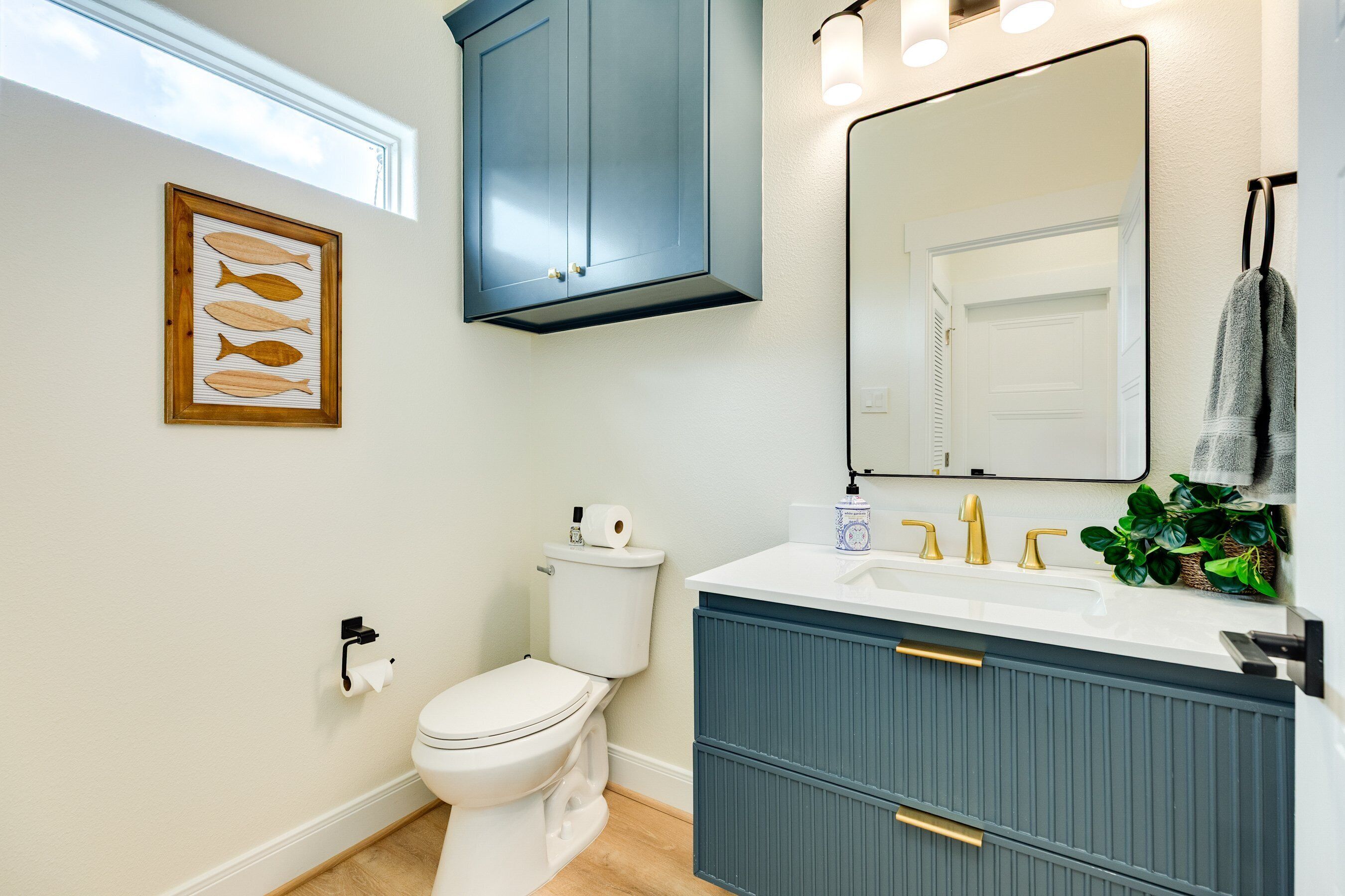 A bathroom with a toilet, vanity, and a large mirror.