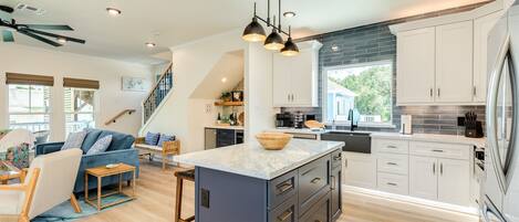 A modern kitchen with a central island, built-in cabinets, and a large window.