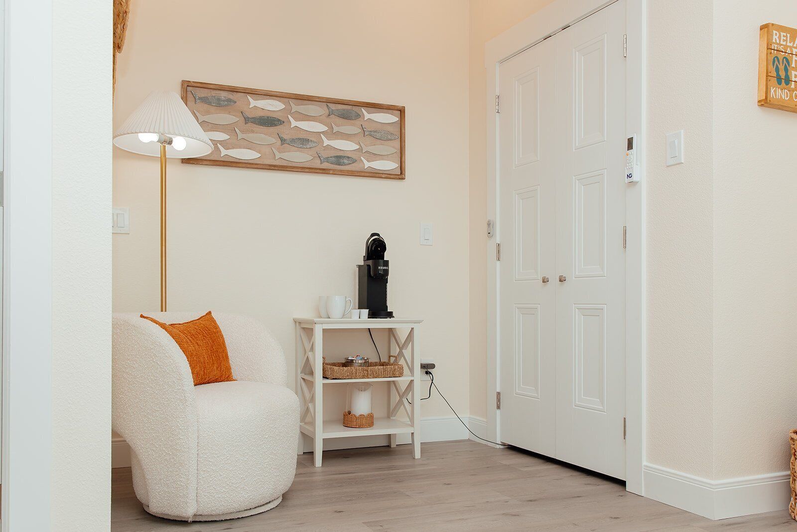Una habitación acogedora con un sillón mullido, una cafetera y una obra de arte enmarcada en la pared.