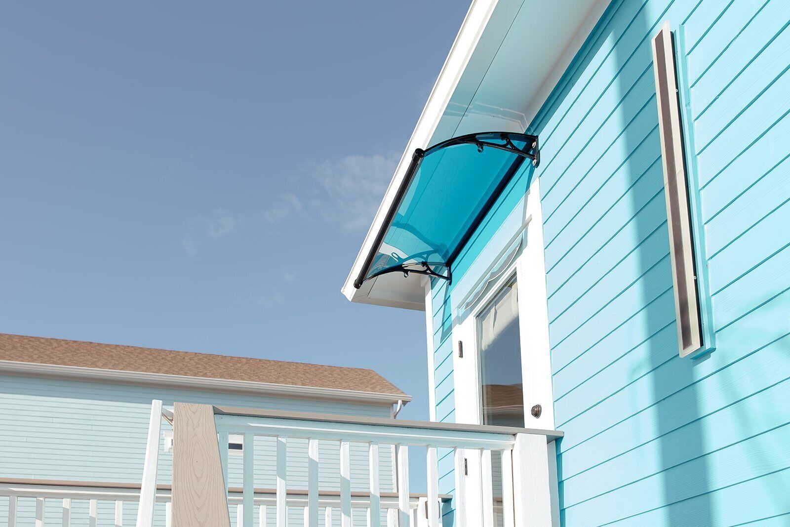 Une maison avec un revêtement extérieur bleu clair et une clôture blanche.