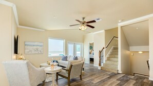 A spacious living room with a wooden floor, a ceiling fan, a sofa, and a dining table. - Twin Palms Paradise (Galveston)