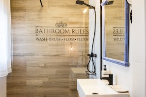 Een badkamer met een houten wand, een wastafel met spiegel en een douchehoek.