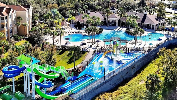 A resort with a large pool area, water slides, and a surrounding landscaped garden. - 3 Miles to Disney! Free Heated Saltwater Pool & Spa, Star Wars Game Room, BBQ! (Kissimmee)