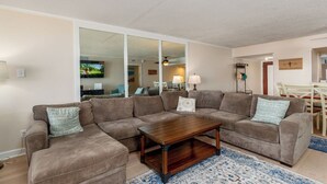 A living room with a sectional sofa, a wooden coffee table, and a patterned rug.