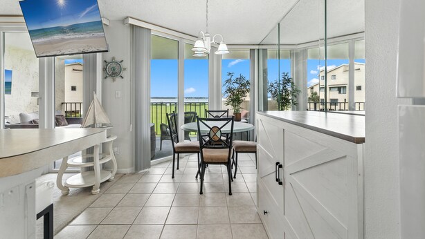 A modern kitchen with a dining area, large windows, and a view of the ocean. - Santa Rosa Dunes 912 | Olympic Size Pool & More | My Beach Getaways (Pensacola Beach)