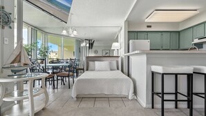 A modern hotel room with a large bed, a dining area, and a kitchen. - Santa Rosa Dunes 912 | Olympic Size Pool & More | My Beach Getaways (Pensacola Beach)