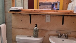 A bathroom with a toilet, sink, and mirror.