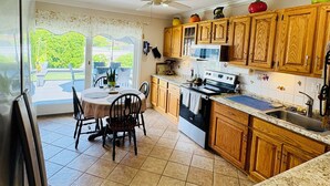 A kitchen with wooden cabinets, a stove, and a dining area with chairs and a table.