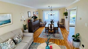 A spacious living room with a sofa, a round coffee table, and a dining area with a table and chairs.