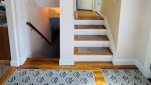 A staircase with wooden steps and white walls, leading to a door.
