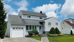 A two-story house with a garage, a paved driveway, and a well-maintained lawn.