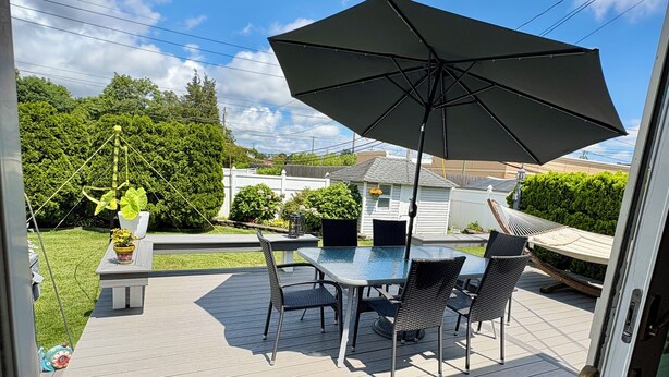 An outdoor patio with a table and chairs, a large umbrella, and a decorative hanging plant.