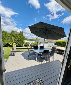 An outdoor patio with a table and chairs, a large umbrella, and a decorative hanging plant.