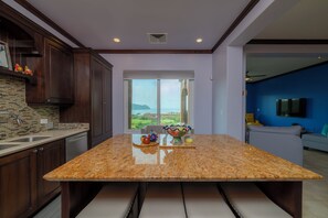 A kitchen with granite countertops, dark wooden cabinets, a large window, and a view of the outdoors. - AltaVista 4C 3 bdr Ocean View in Los Suenos (Playa Herradura)