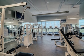 A modern gym with various exercise machines, large windows, and a clear view of the cityscape. - Sunset Suite | Skyline Views | King + Twin Sofa Includes Parking (Miami)