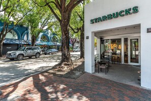 A Starbucks with a brick-paved sidewalk and trees. - Modern 3BR/3.5BA Grove Condo | Views, Balconies, Full Kitchen + 3 Parking (Miami)