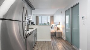 A modern kitchen with stainless steel appliances, a central island, and a view of the city through large windows. - Stylish Studio at Hotel Arya | King Bed, Full Kitchen + City View Balcony (Miami)