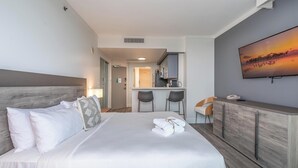A hotel room with a bed, a desk, a kitchenette, and a TV on the wall. - Stylish Studio at Hotel Arya | King Bed, Full Kitchen + City View Balcony (Miami)