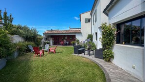 A modern house with a patio area featuring outdoor furniture and a barbecue.