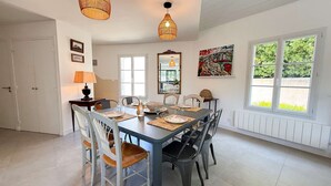 A dining area with a table set for six, surrounded by chairs, a lamp, and artwork on the walls.