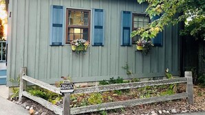 Ein kleines, eingeschossiges Gebäude mit hellgrüner Fassade und blauen Fensterläden. Vor der Tür steht eine hölzerne Bank, und ein Schild mit der Aufschrift 'PRIVATE PROPERTY' ist angebracht.