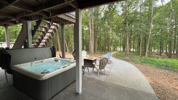 Een hottub onder een houten pergola met uitzicht op een bebost gebied.
