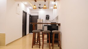 Cocina con refrigerador, microondas y cafetera. Hay tres taburetes de madera con asientos acolchados.