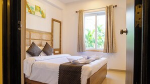 Una cama bien hecha con cubrecama acolchado, cabecera de madera y ventana con cortinas.