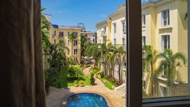 Un patio con piscina, palmeras y vistas a edificios de varios pisos.