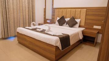 A neatly made bed with a wooden headboard, a bedside table, and a mirror on the wall.