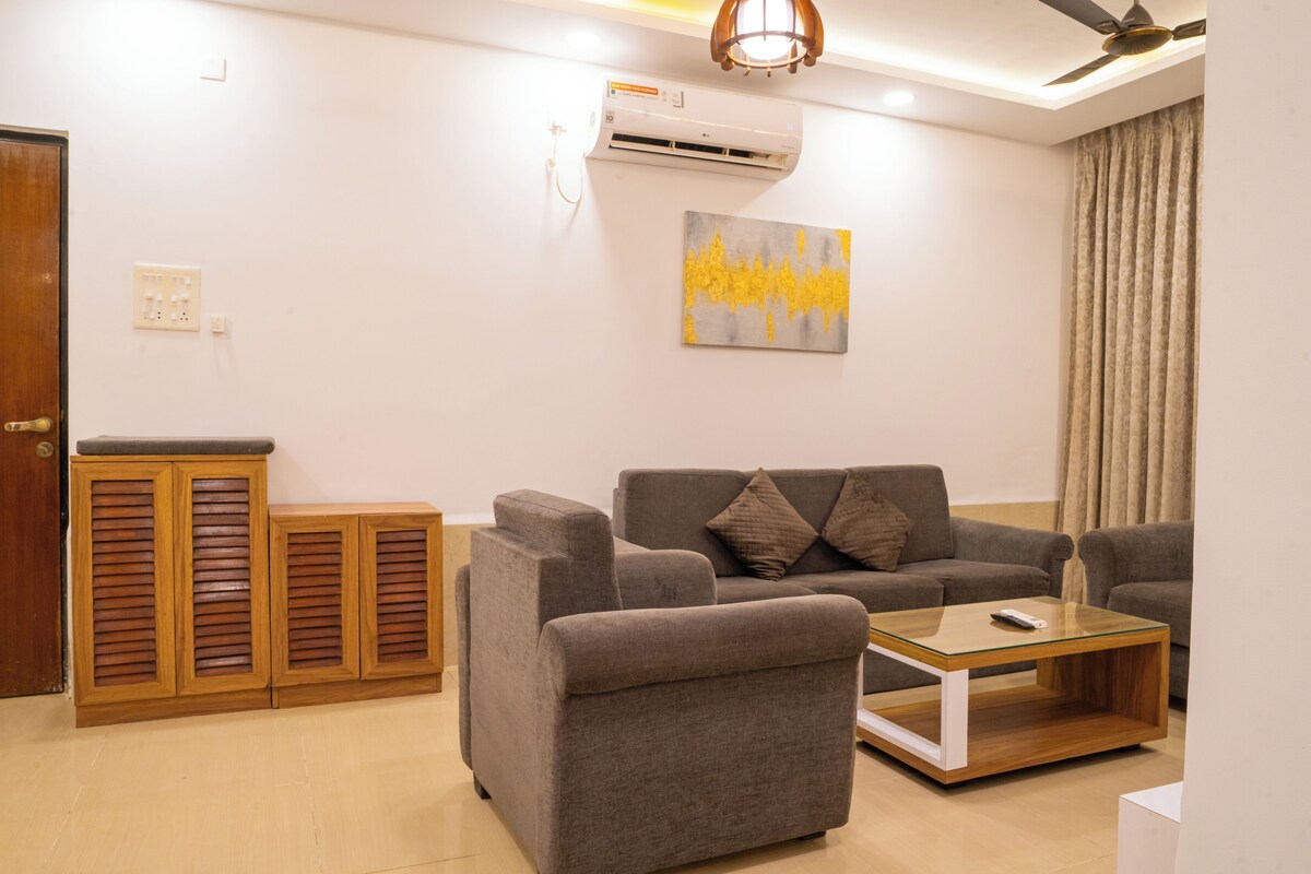 A living room with a grey sofa, a glass coffee table, and wooden cabinets.
