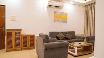 A living room with a grey sofa, a glass coffee table, and wooden cabinets.